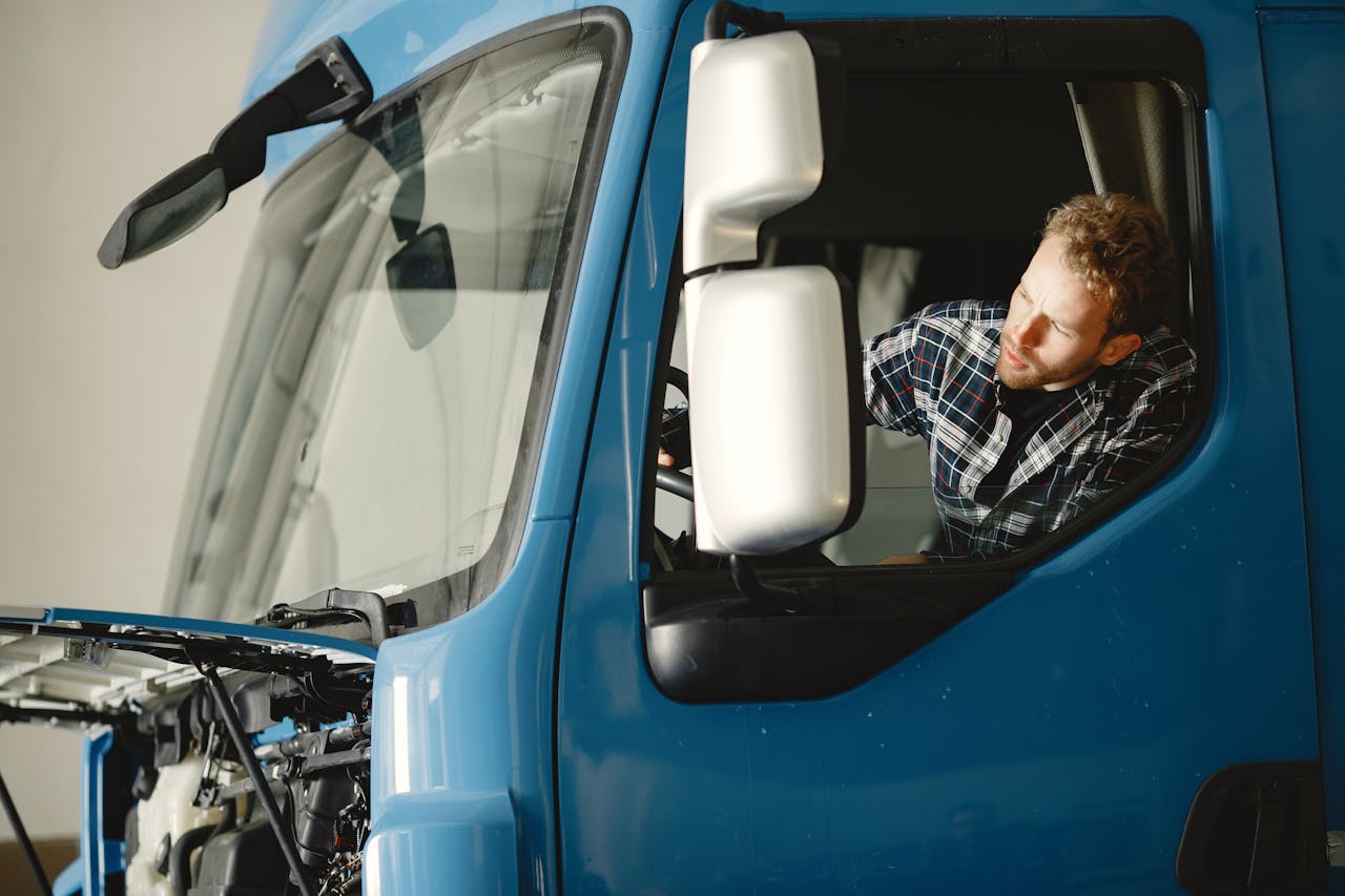 services-04 A mechanic checks the engine of a blue truck indoors, focusing on maintenance.